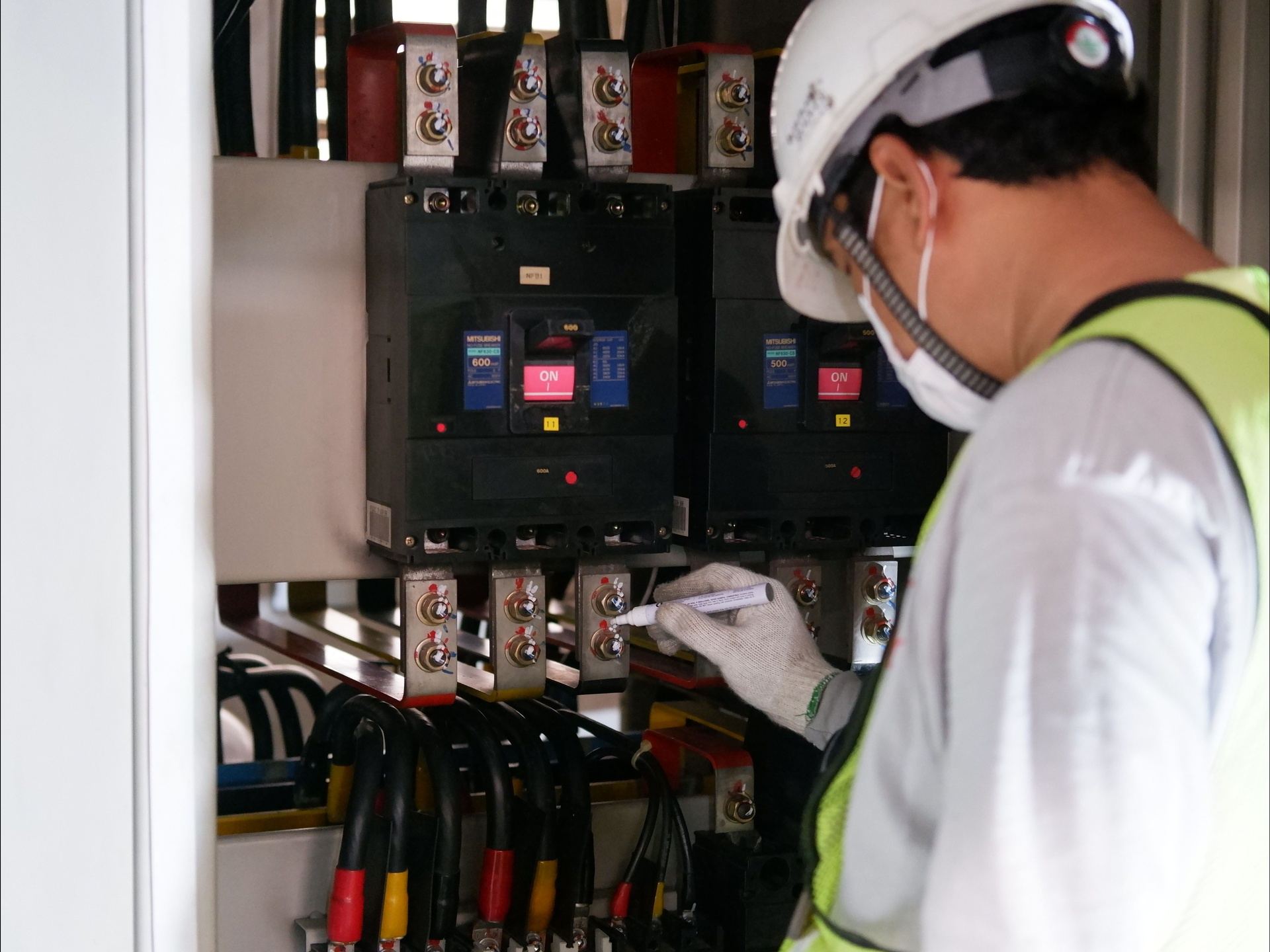 Technician marking and checking a commercial distribution panel during an electrical compliance inspection